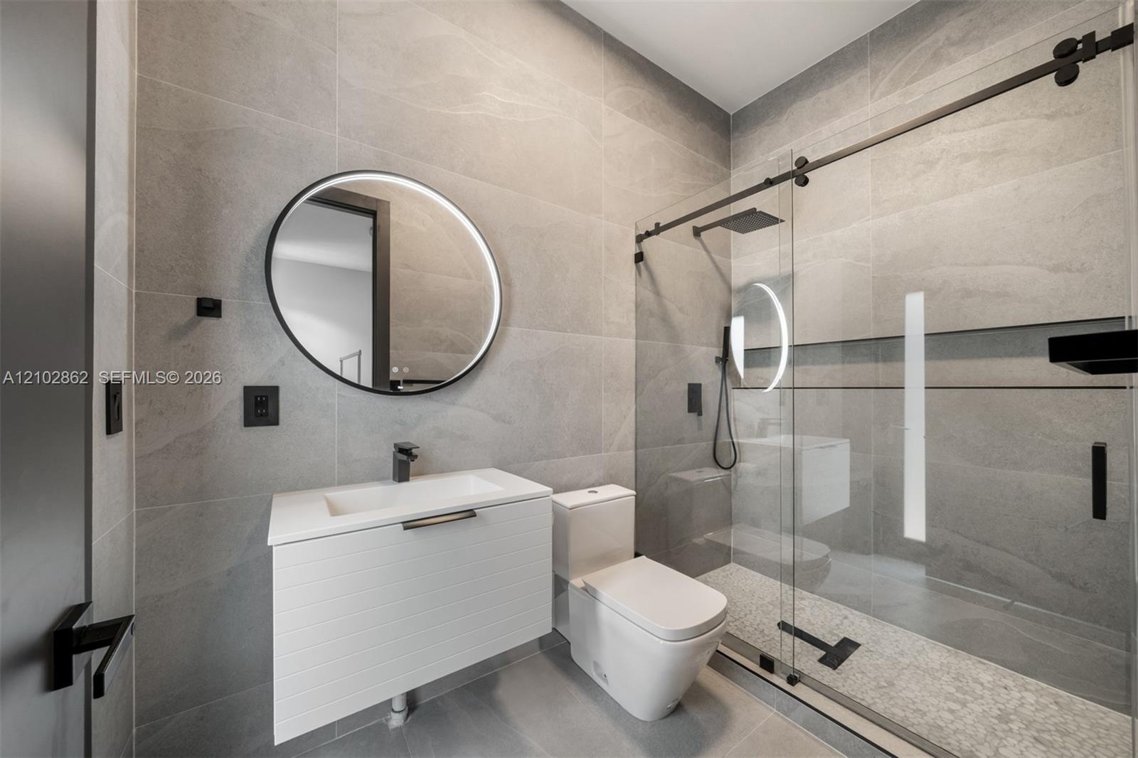 Room featuring wood-finish flooring, wall-mounted ductless air conditioning unit, tall vertical window, and high-contrast dark door casing