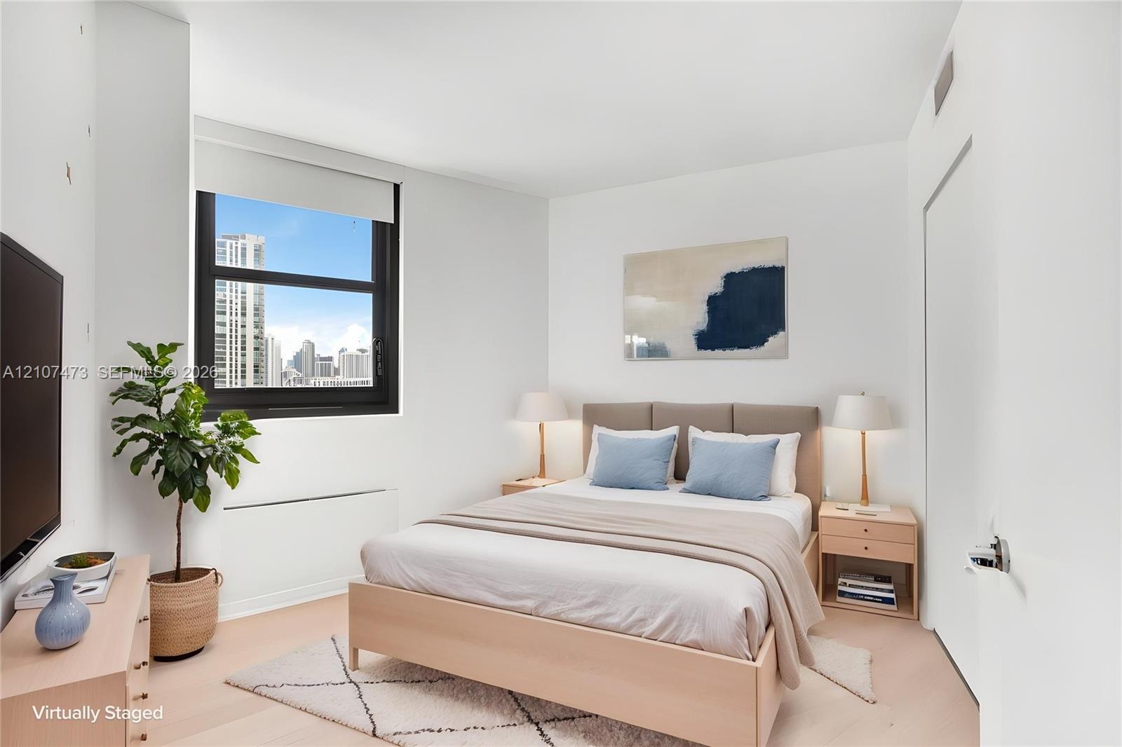 Neutral-toned interior featuring wood-finish flooring, a large window with black framing, and a urban skyline backdrop