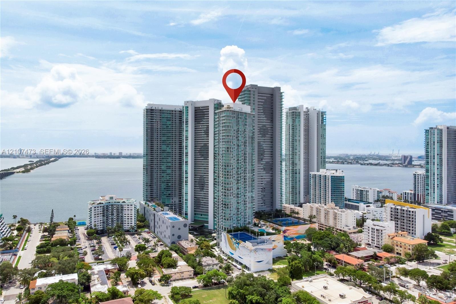 High-rise residential tower featuring a glass facade, expansive water proximity, and a multi-level structure with prominent podium parking and podium-