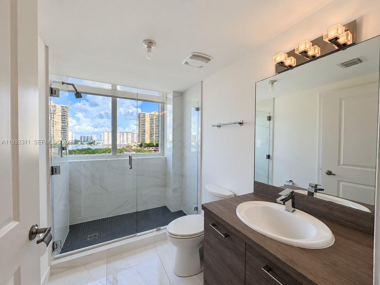 Interior space featuring polished tile flooring, neutral walls, and a full-height window with water and skyline scenery