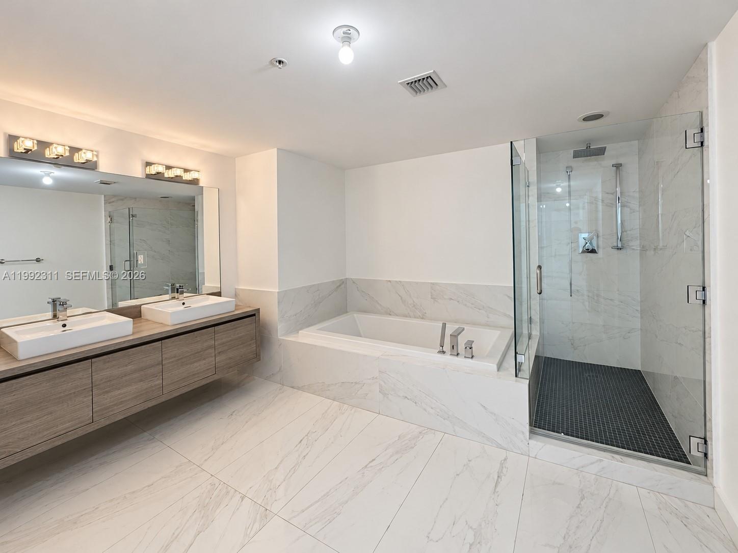 Interior hallway featuring light-toned tile flooring, white walls, flush-mount ceiling lighting, and louvered closet doors