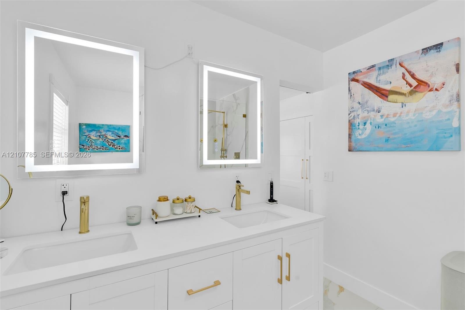 Dual-sink vanity featuring integrated rectangular basins, white stone-finish countertop, and gold-toned hardware, complemented by two rectangular LED-