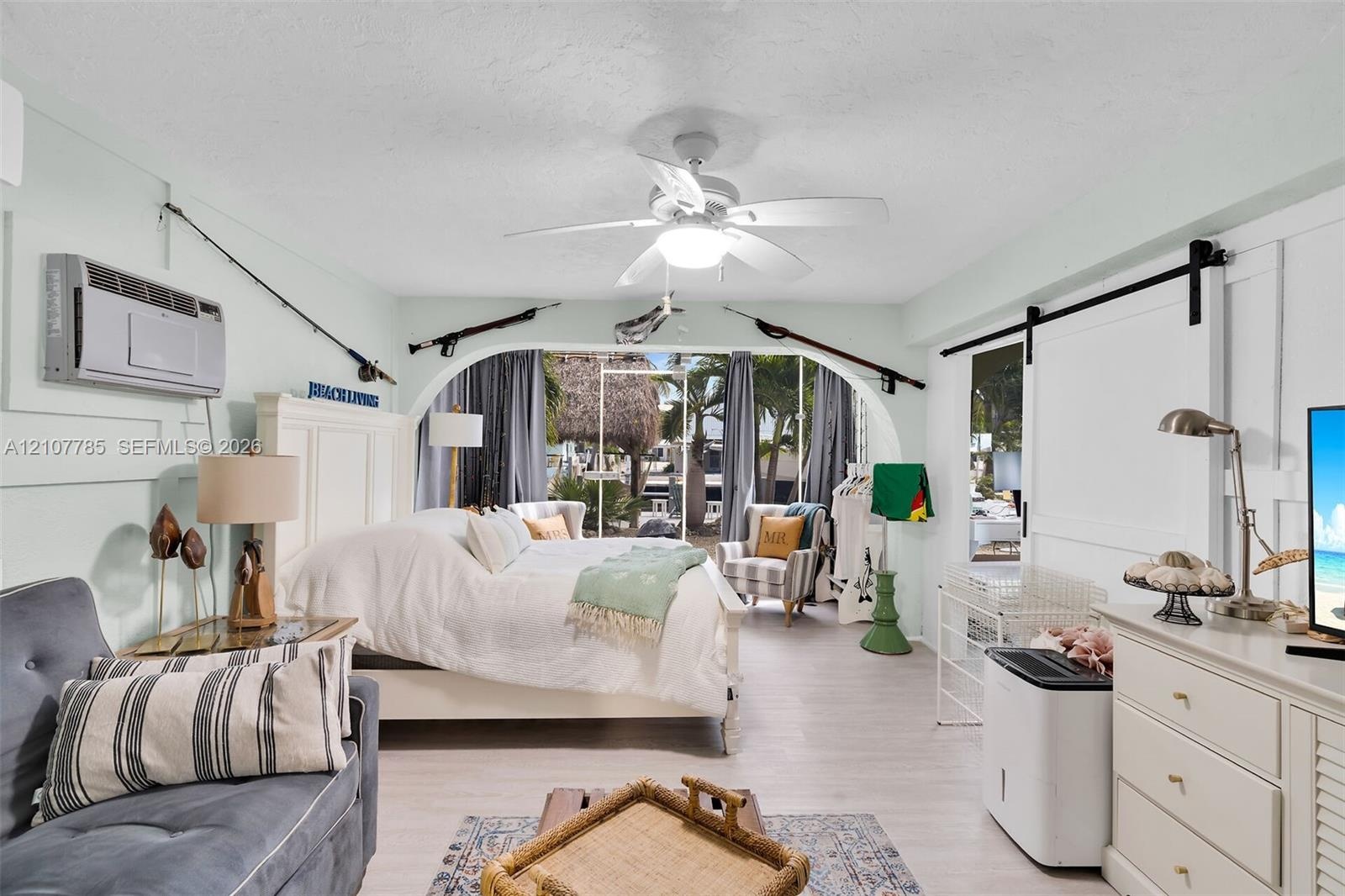 Archway opening with wood-finish flooring, board-and-batten wall detailing, sliding barn door, and ceiling-mounted fan with integrated lighting