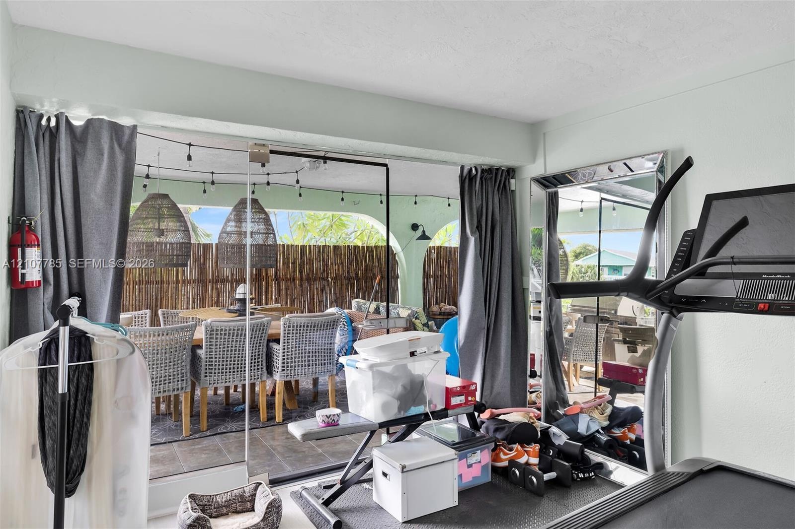 Large glass sliding doors opening to a covered patio featuring arched architectural details and tile flooring