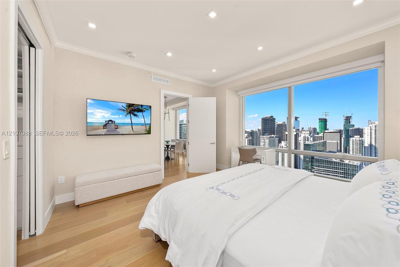 Floor-to-ceiling windows with urban skyline scenery, wood-finish flooring, recessed ceiling lighting, and crown molding