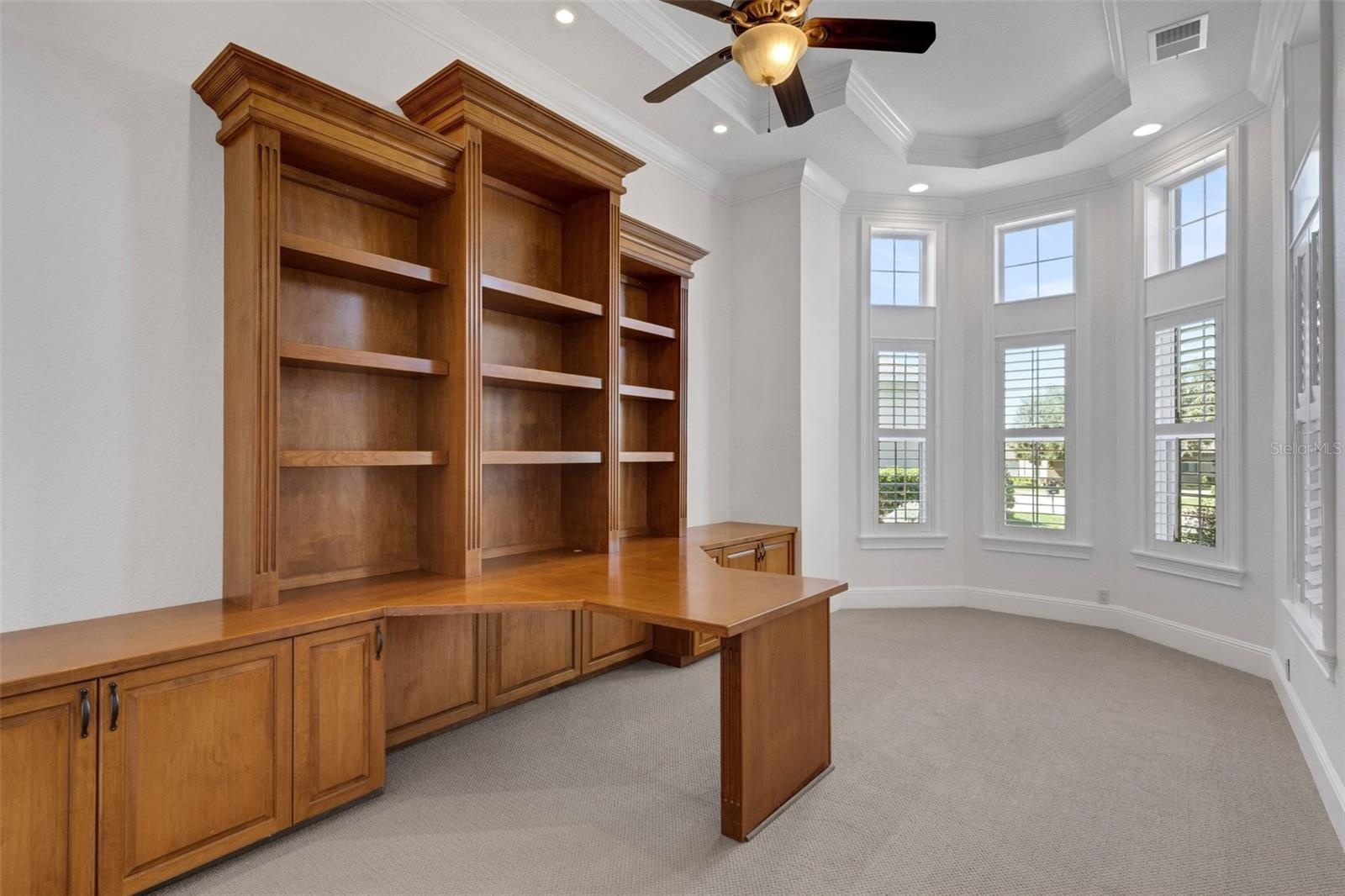 The office has a massive built-in two-person desk and shelf system.