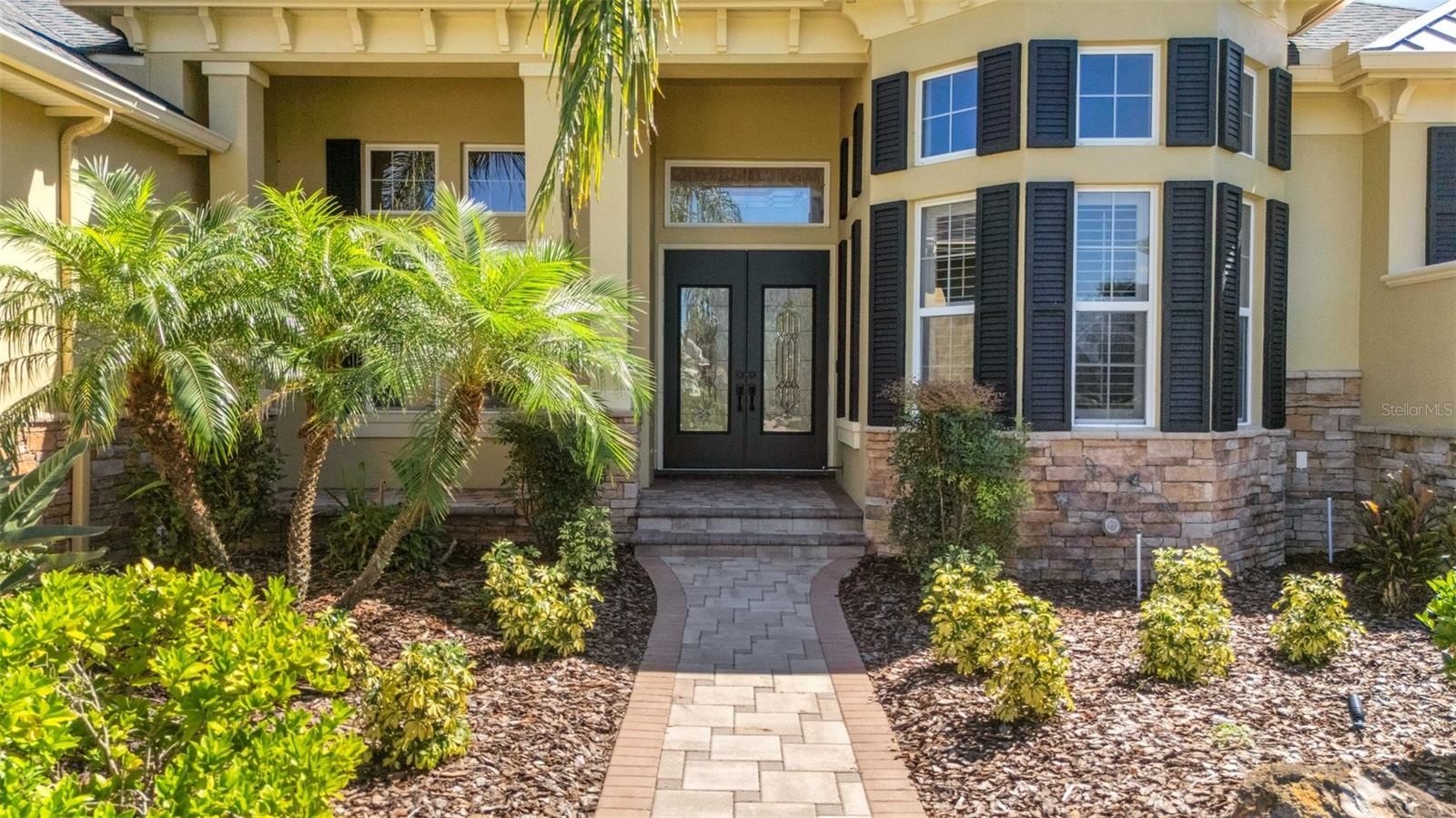 The wide deep elevated entry boasts stone accents, brick pavers and dual leaded glass entry doors.