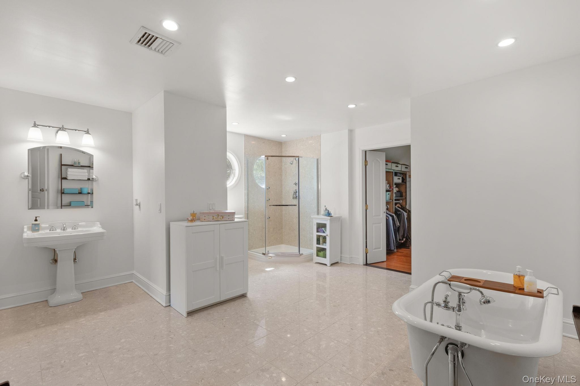 A beautifully appointed primary bath offers a luxurious retreat, featuring an inviting soaking tub, glass-enclosed shower, and spacious walk-in closet