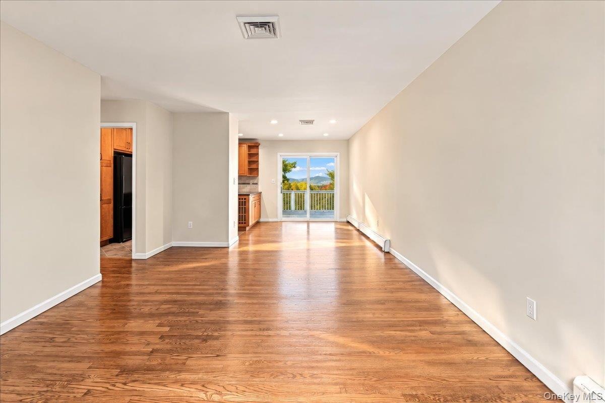 Bright living room with newly refinished hardwood floors flowing seamlessly into the dining room and kitchen, offering beautiful river views.
