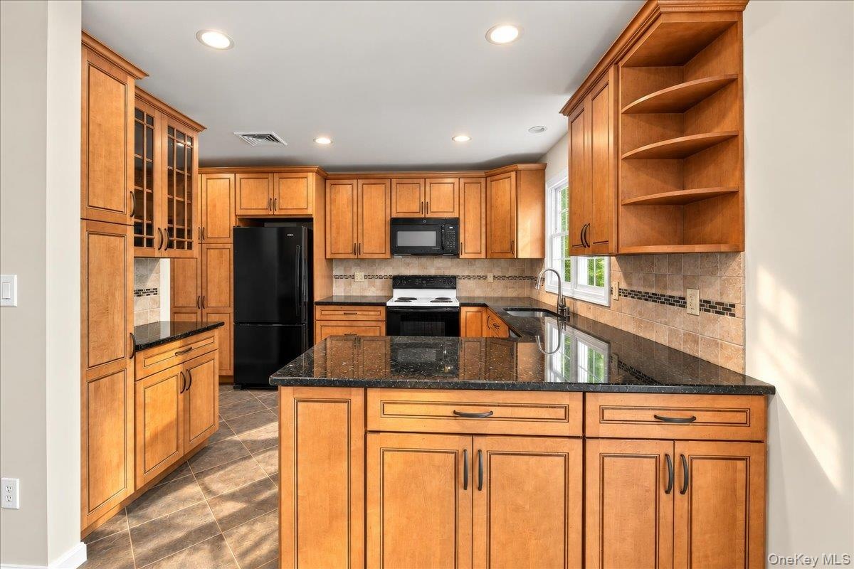 Stone countertops, recessed lighting, and an abundance of cabinet storage and counter space make this kitchen both functional and inviting.