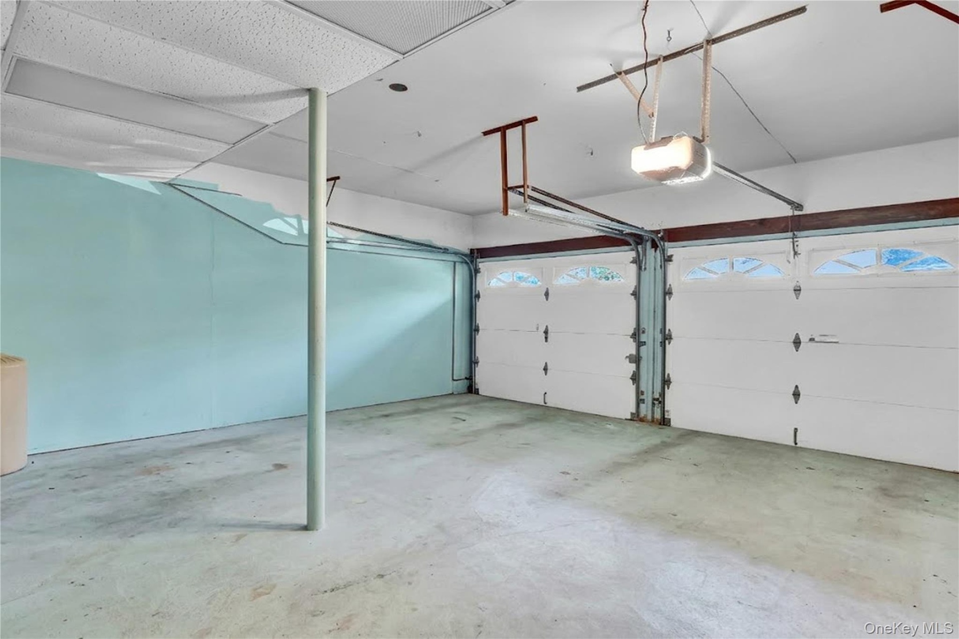 Attached two-car garage featuring dual overhead doors with glass panel inserts, concrete flooring, and ceiling-mounted automatic door openers