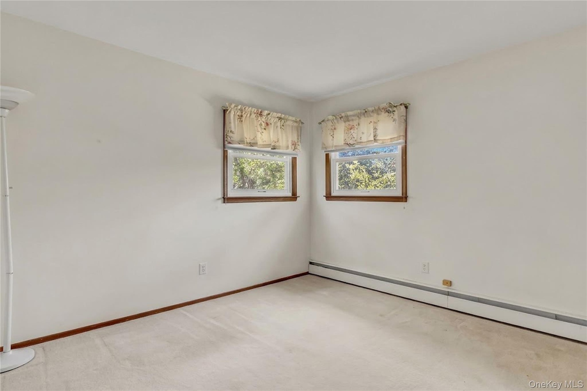 Neutral-toned interior featuring dual windows with wood trim and wall-to-wall carpeting