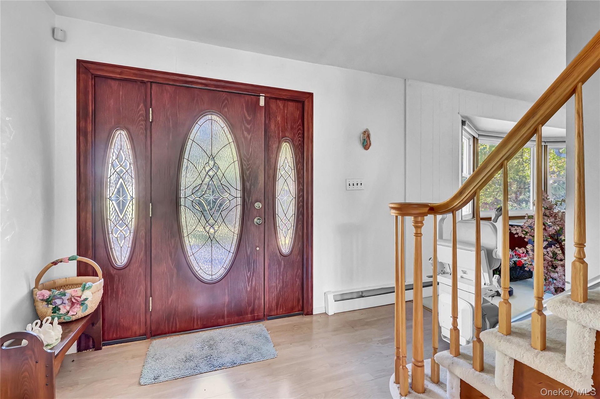 Entryway featuring a wood-finish door with decorative glass inserts, a wood-finish handrail, and carpeted stairs