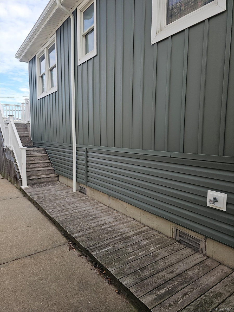 Exterior featuring board-and-batten and horizontal lap siding, white trim, wood-plank decking, and a white railing system