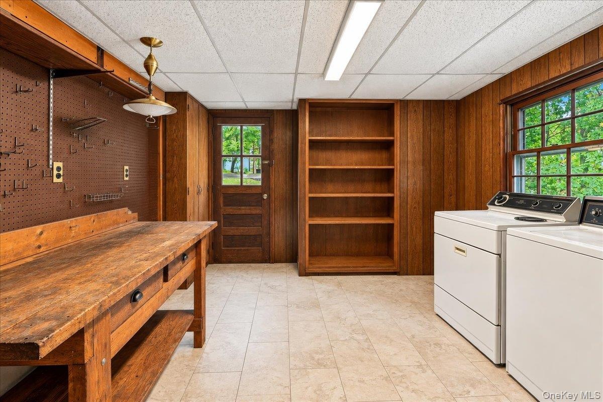 Functional utility room featuring a washer and dryer, workbench, and ample storage, with convenient direct access to the driveway.