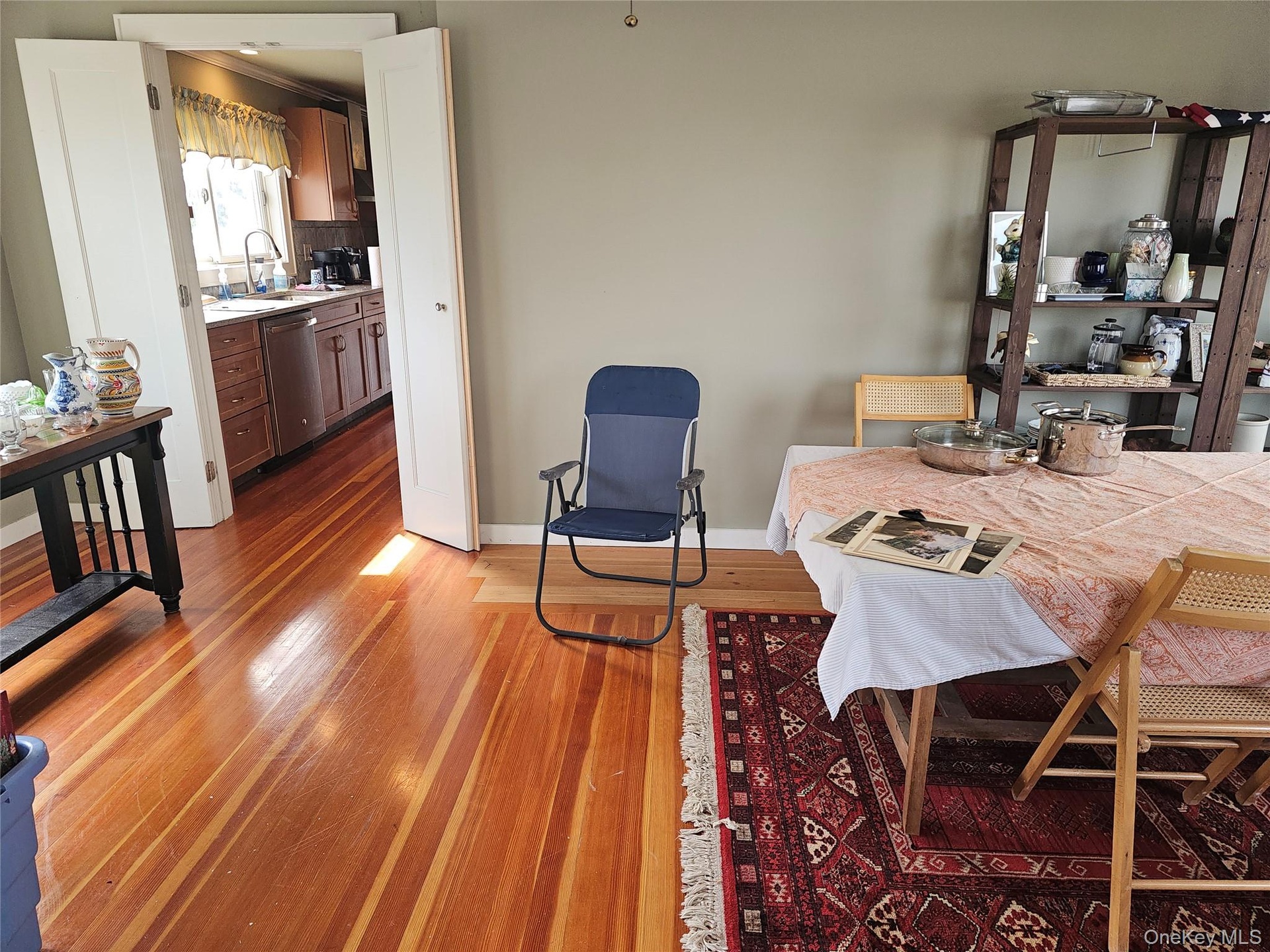 Wood-finish flooring, double-door entryway, and kitchen featuring wood cabinetry and an under-mount sink