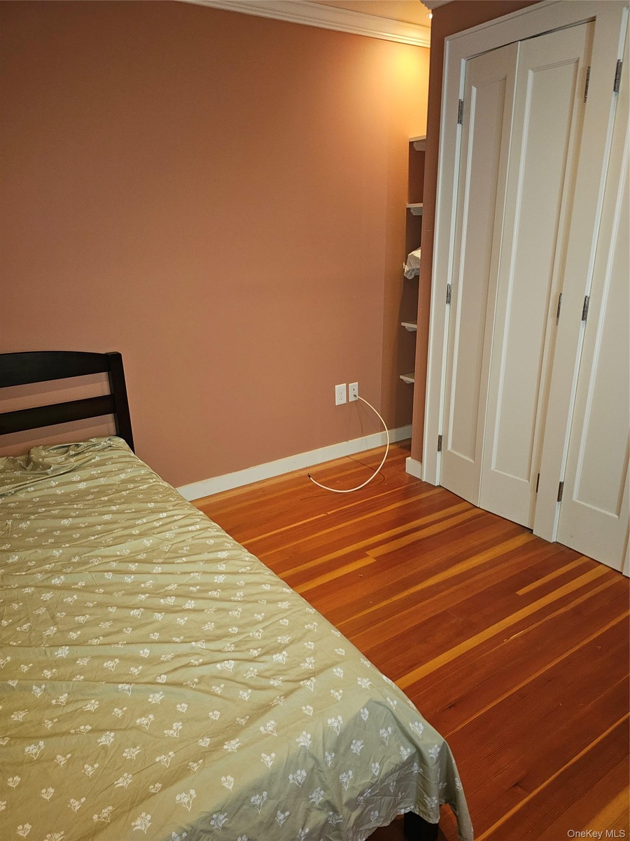Wood-finish flooring, white paneled bi-fold closet doors, and built-in shelving