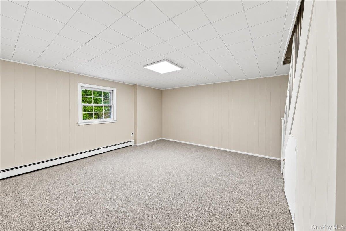 Inviting lower-level family room featuring brand-new carpeting and fresh paint, offering a comfortable space for movie nights, family gatherings, and 