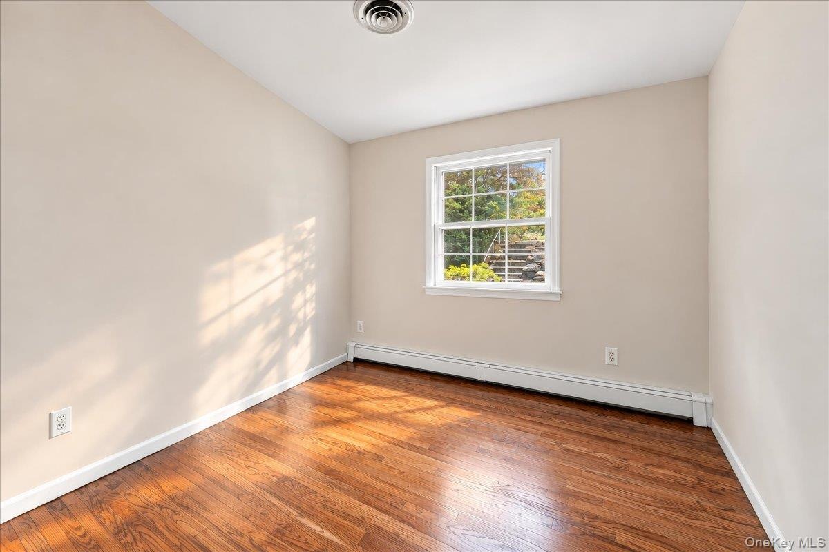 Bright and airy bedroom featuring newly refinished hardwood floors and fresh paint, creating a clean, welcoming feel.