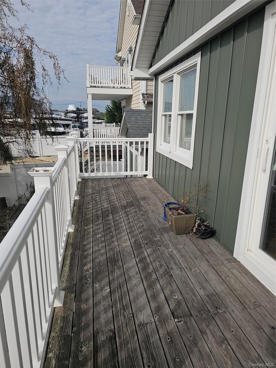 Covered deck featuring vertical siding, white railing, and exterior glass door