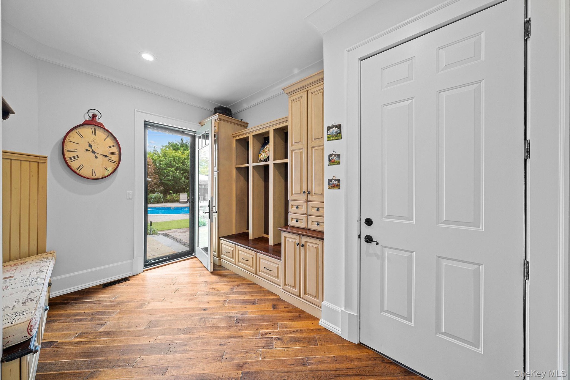 Entryway featuring wood-finish flooring, floor-to-ceiling custom built-in cabinetry, recessed lighting, and a glass-paneled exterior door