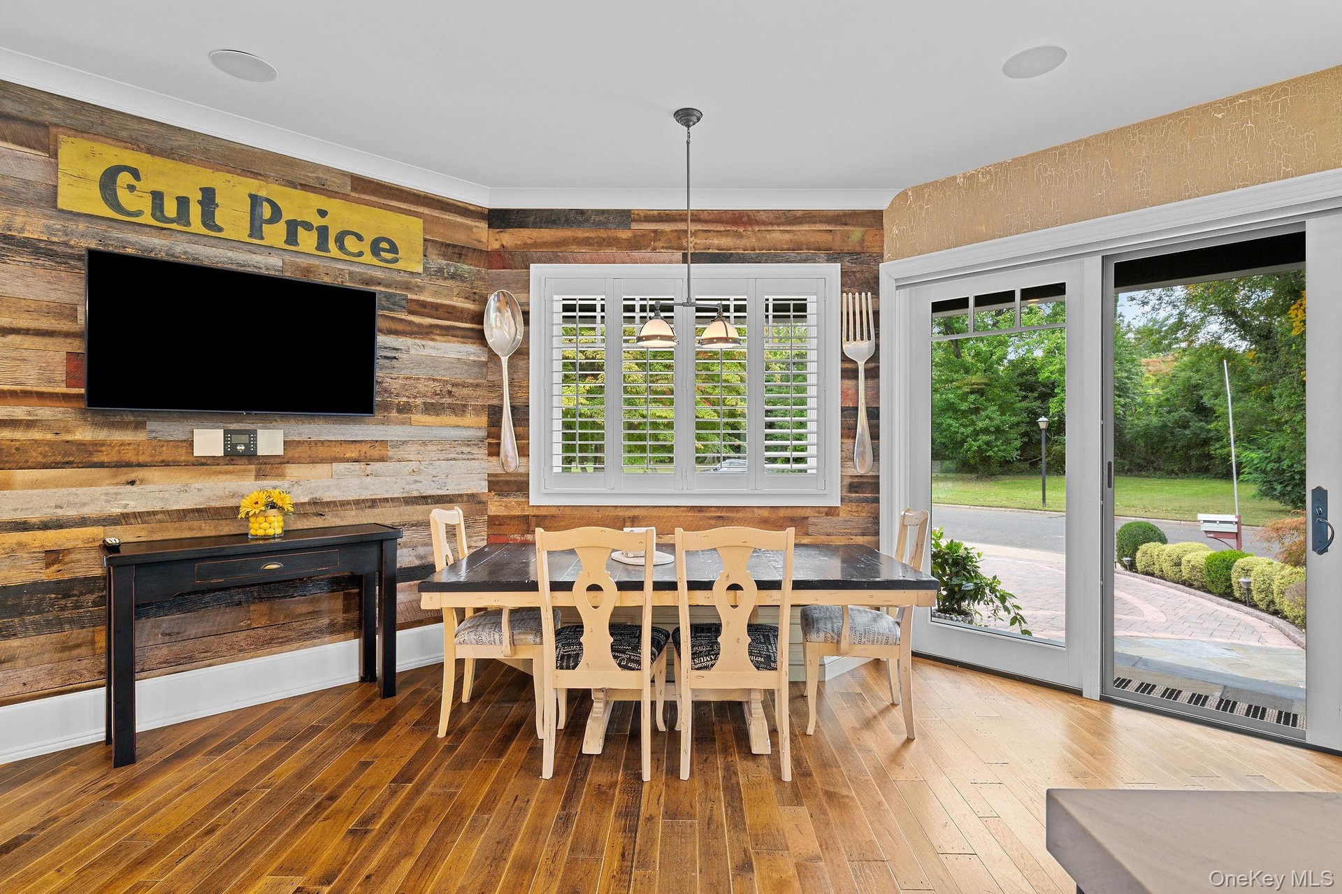 Reclaimed wood accent wall, wood-finish flooring, plantation shutters, and sliding glass doors with exterior access