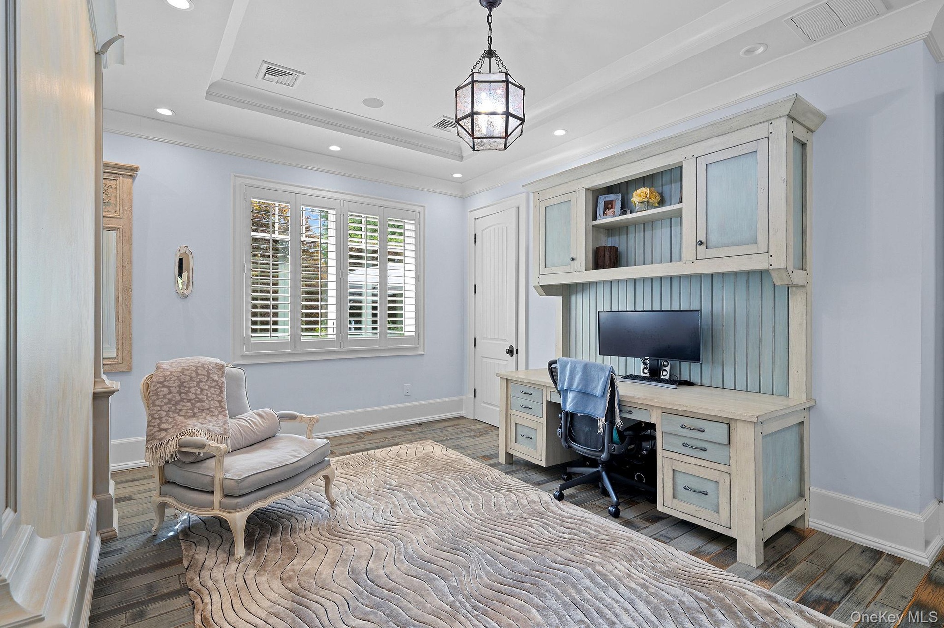 Tray ceiling, built-in cabinetry with beadboard paneling, recessed lighting, polished wood-finish flooring, and plantation shutters