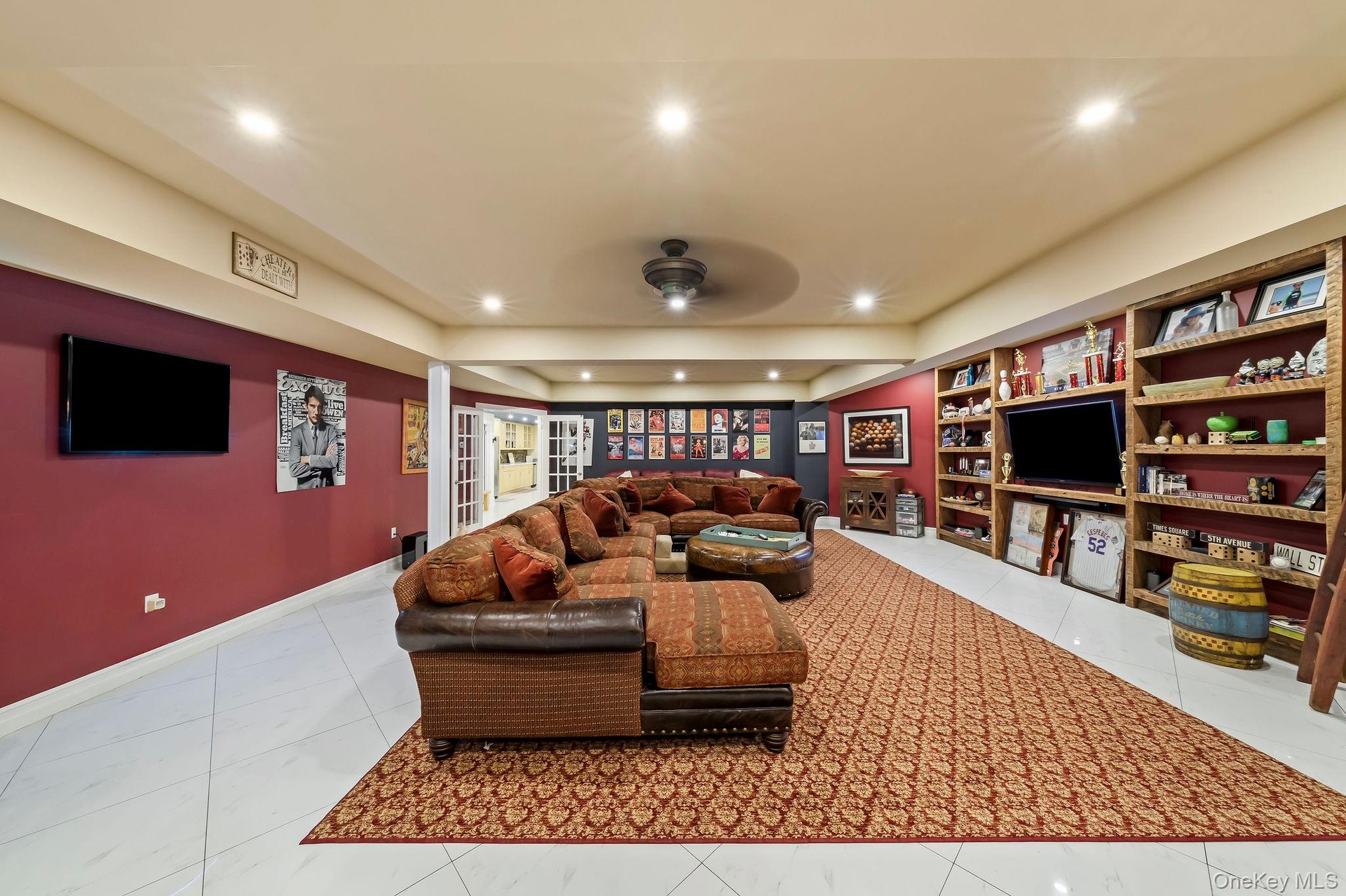 Large recreation space featuring polished tile flooring, recessed lighting, ceiling fan, and extensive built-in wood shelving