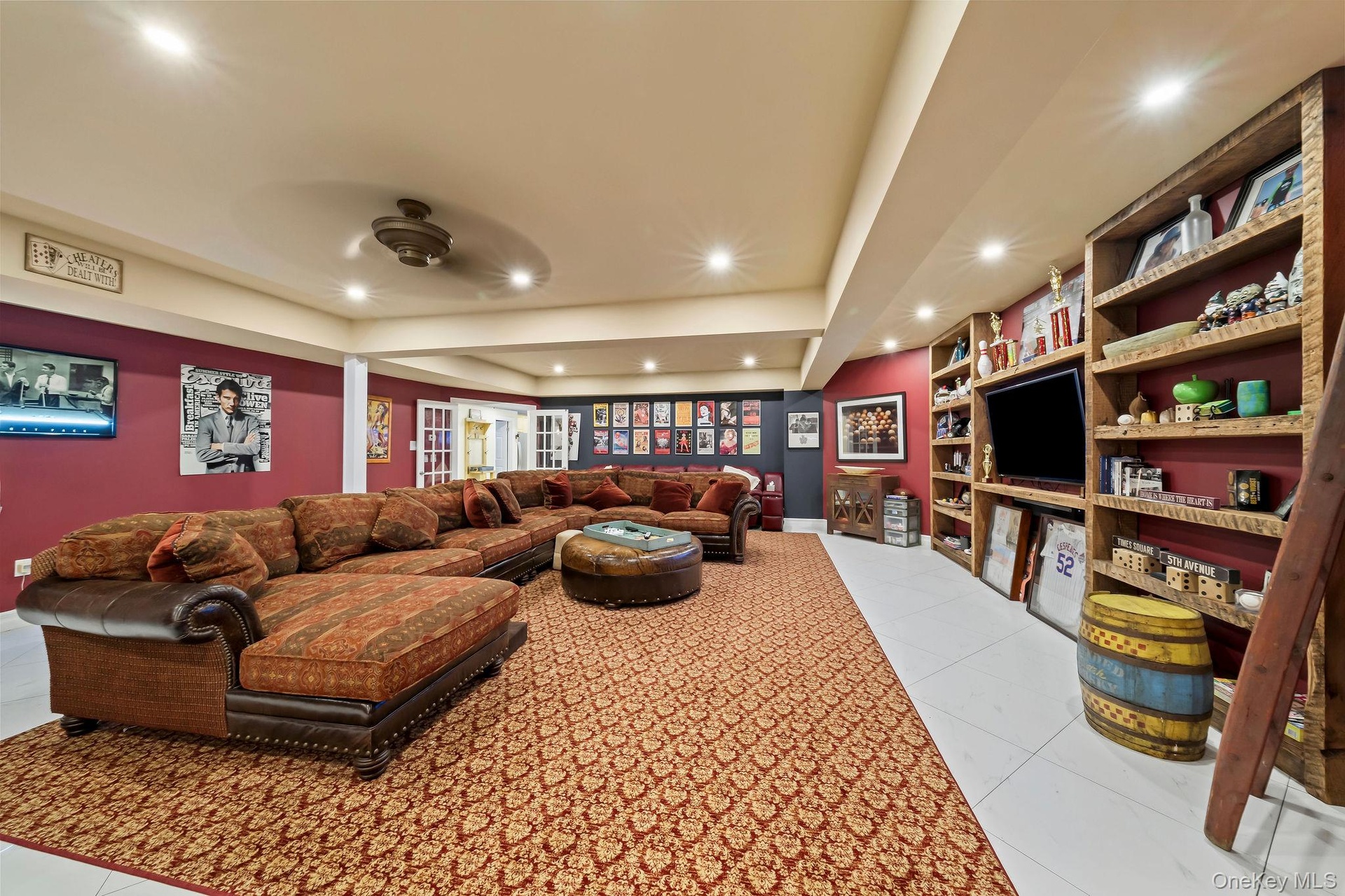 Spacious room featuring floor-to-ceiling built-in wooden shelving, recessed lighting, tile flooring, and French doors