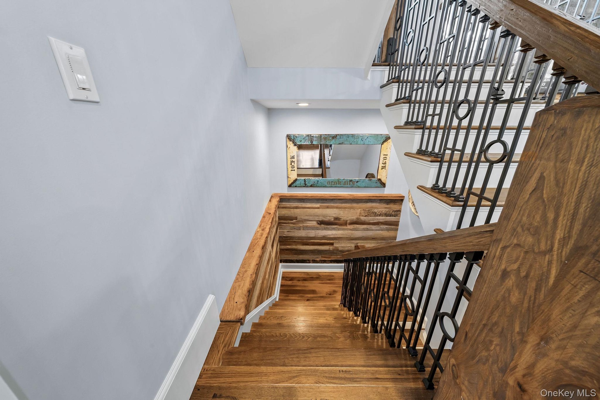 Staircase featuring wood-finish treads, custom metal railings, and a horizontal wood-plank accent wall