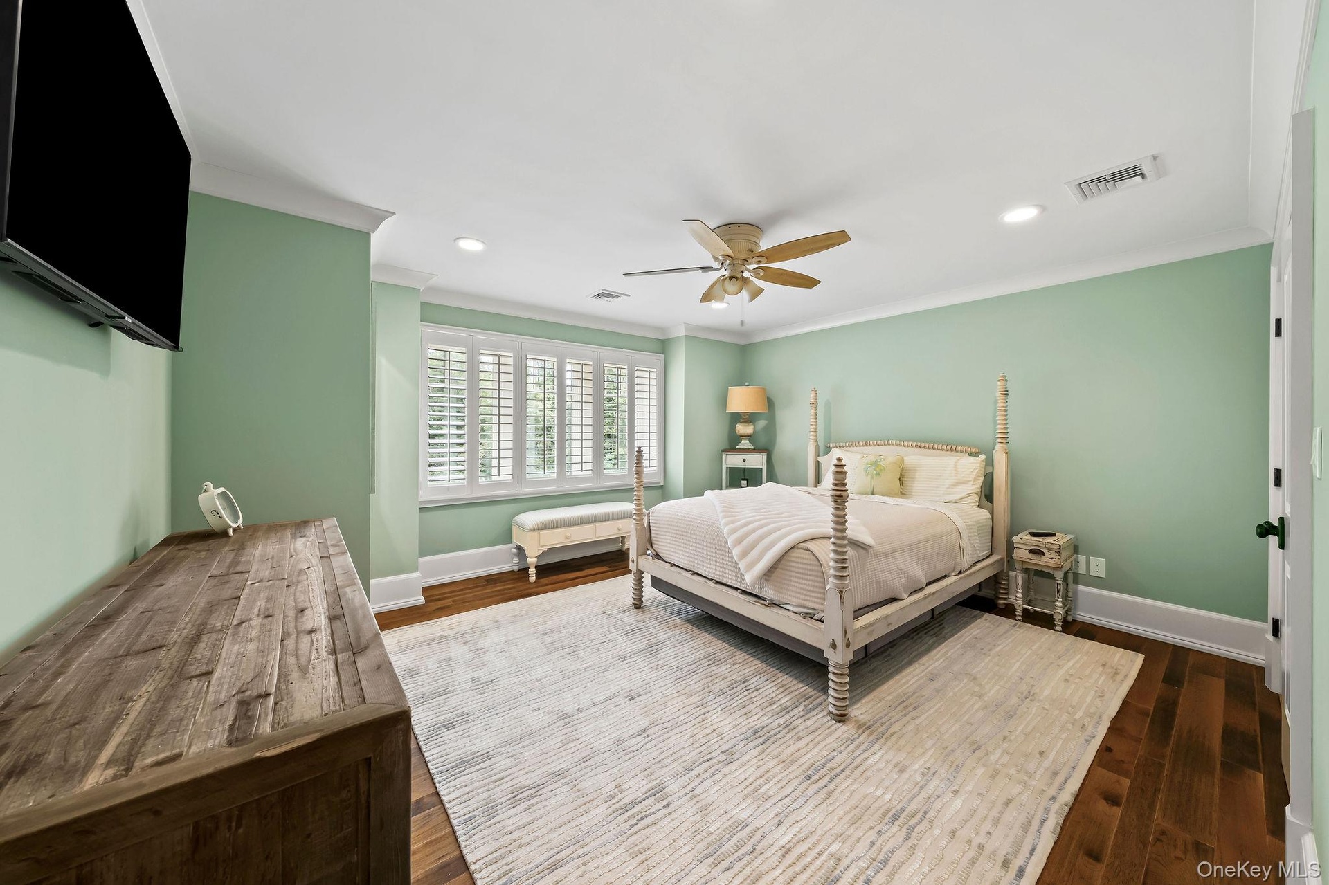 Spacious interior featuring wood-finish flooring, recessed lighting, crown molding, a ceiling fan, and multi-panel plantation shutters