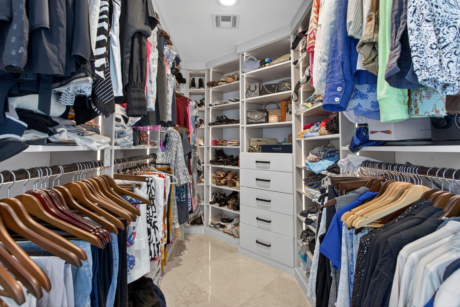 Custom-designed closet with extensive built-in shelving, multiple hanging rods, integrated drawers, an