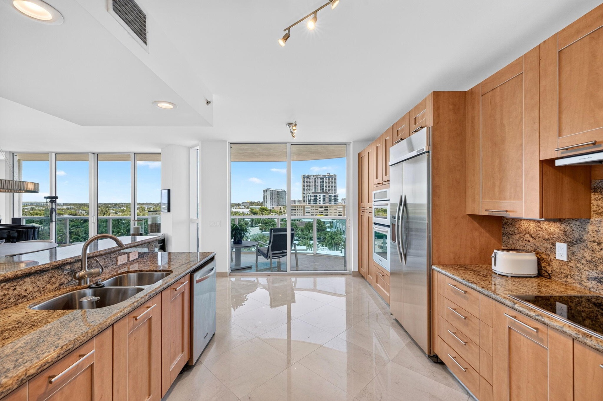Full-height cabinetry with stainless steel appliances, granite countertops, and light-toned tile flooring
