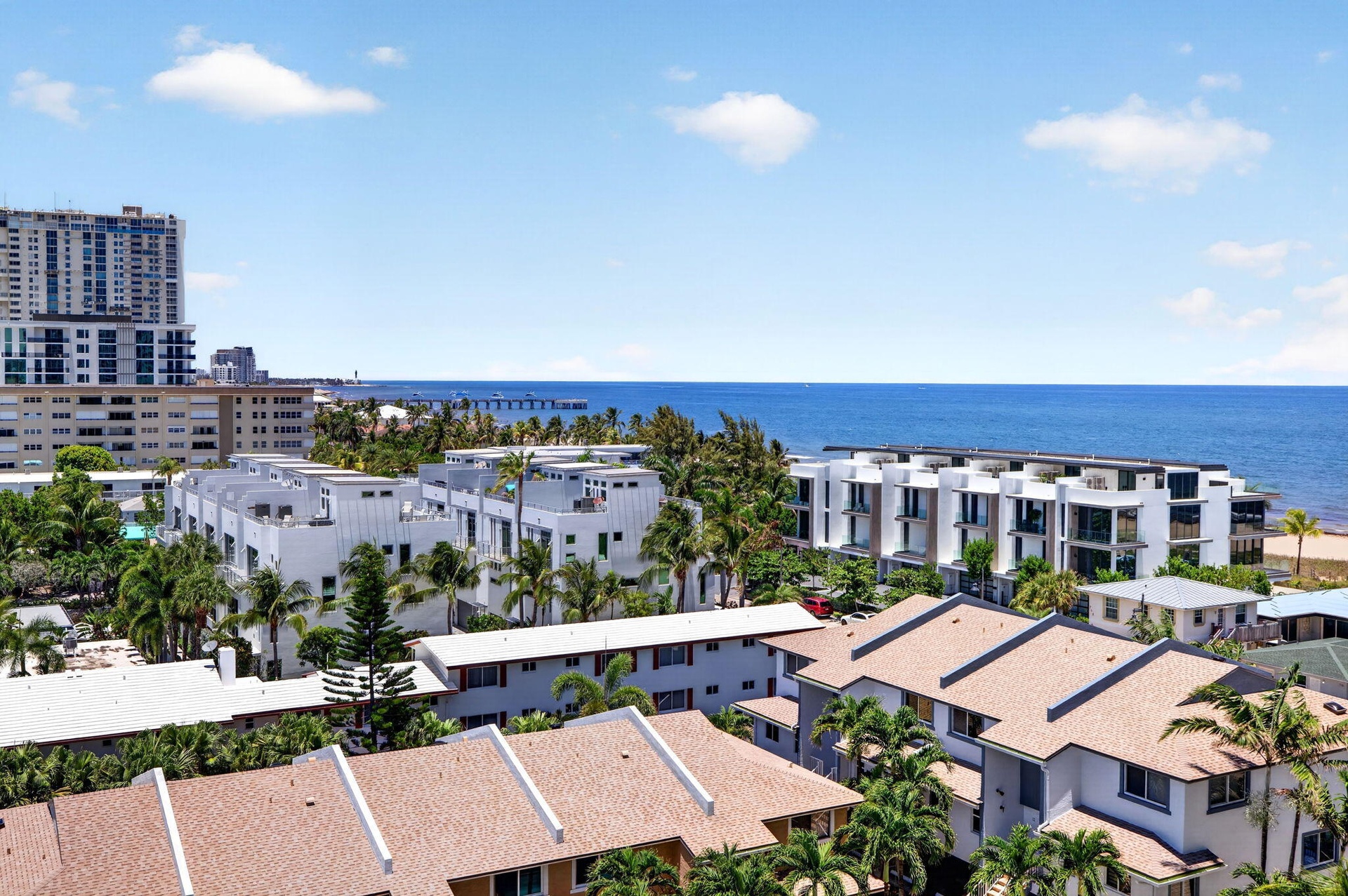 Oceanfront scenery with a distant pier and a mix of residential structures