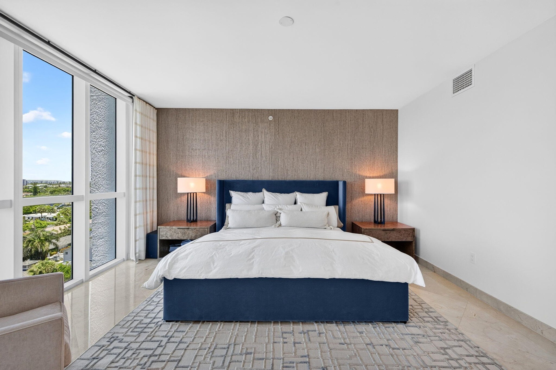 Floor-to-ceiling windows, light-toned tile flooring, textured accent wall, recessed lighting, and wall-mounted air conditioning vent