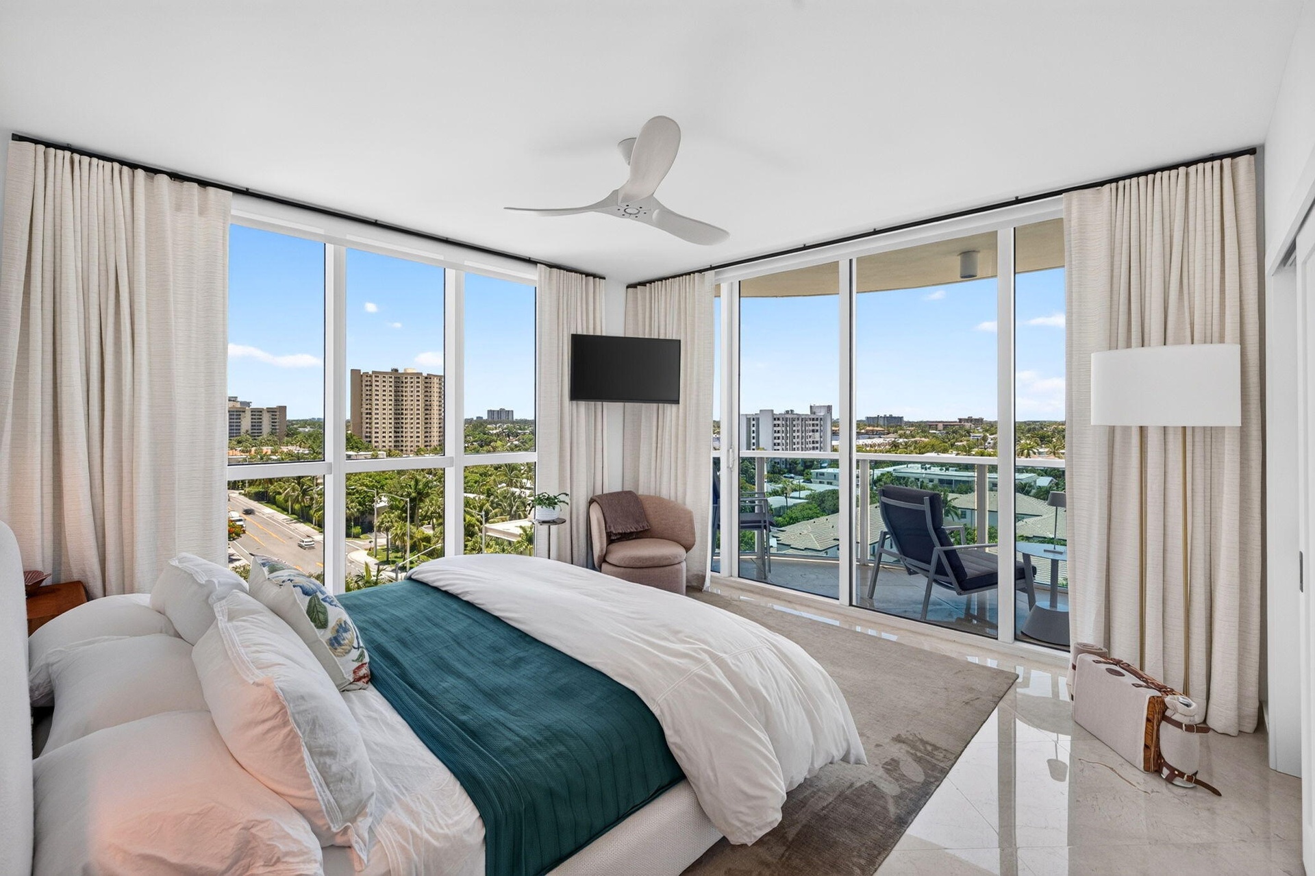 Floor-to-ceiling windows, sliding glass door to exterior balcony, high ceilings, ceiling fan, and marble flooring