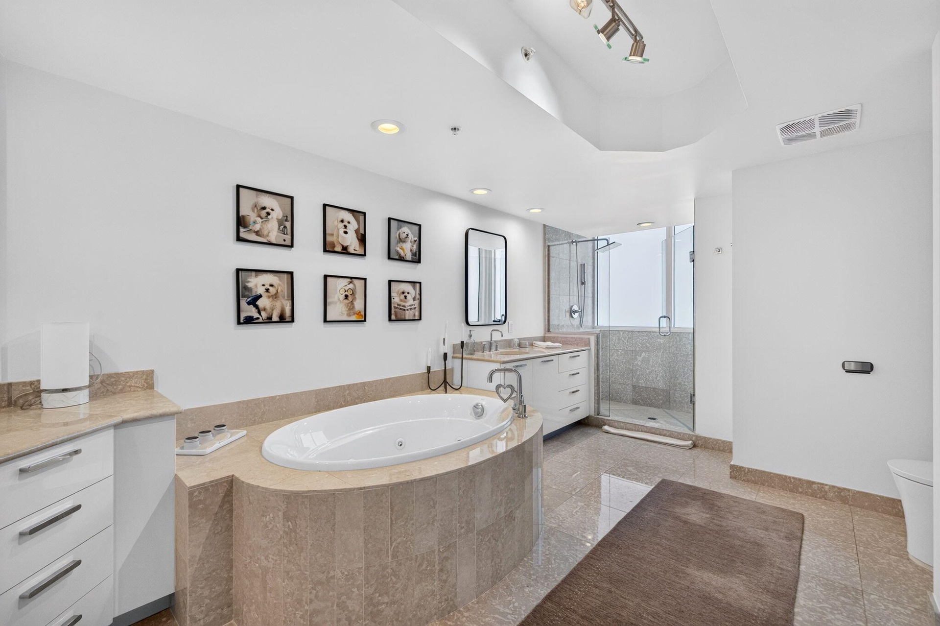 White soaking tub with integrated jets, dual vanity with undermount sinks, glass-enclosed shower, and tile flooring