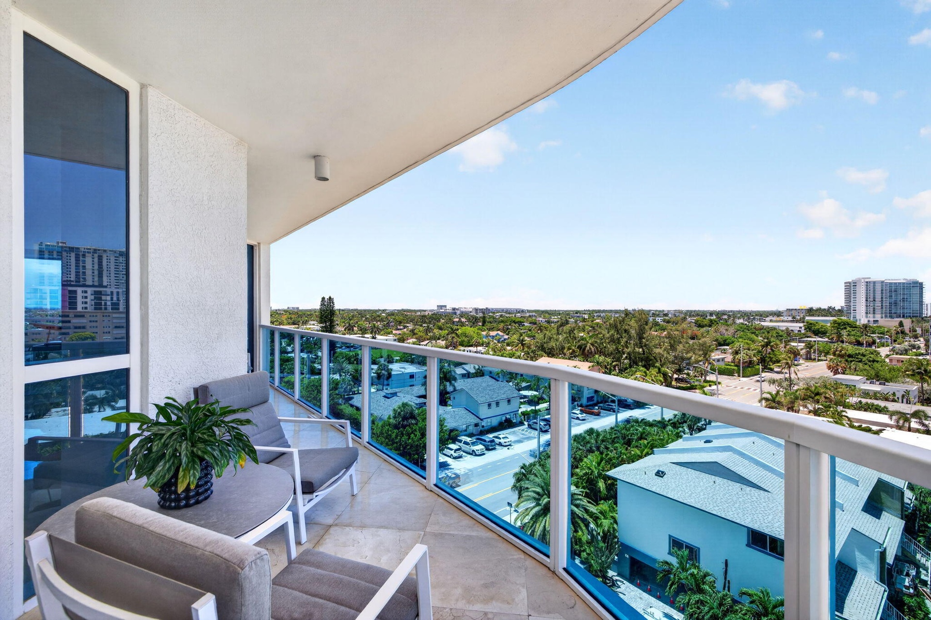 Balcony featuring a glass railing, tiled flooring, and a broad urban landscape