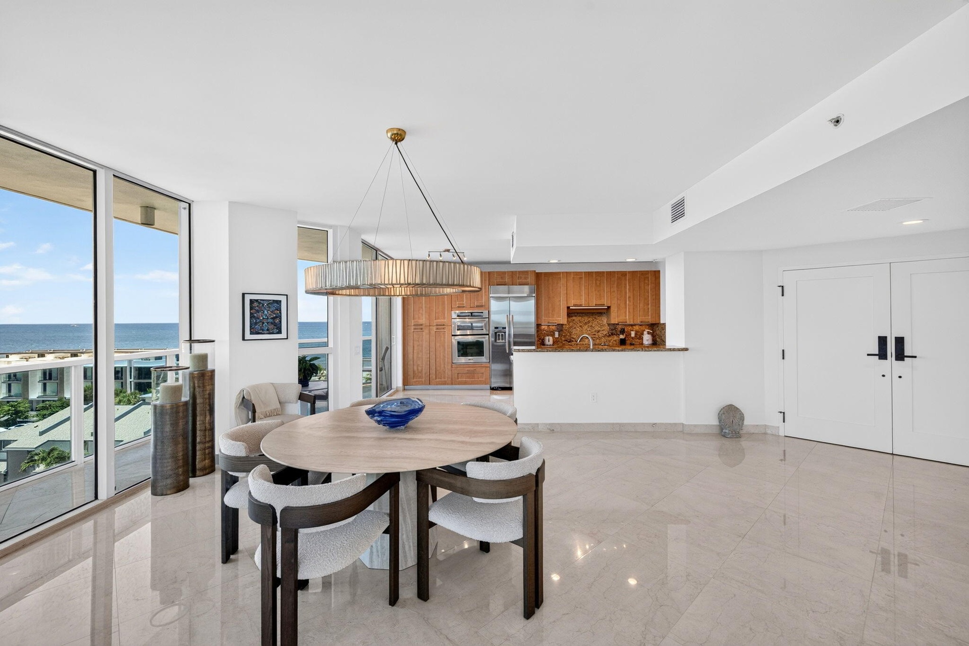 Floor-to-ceiling windows, light-toned polished flooring, modern kitchen with wood cabinetry, stainless steel appliances, and double panel interior doo