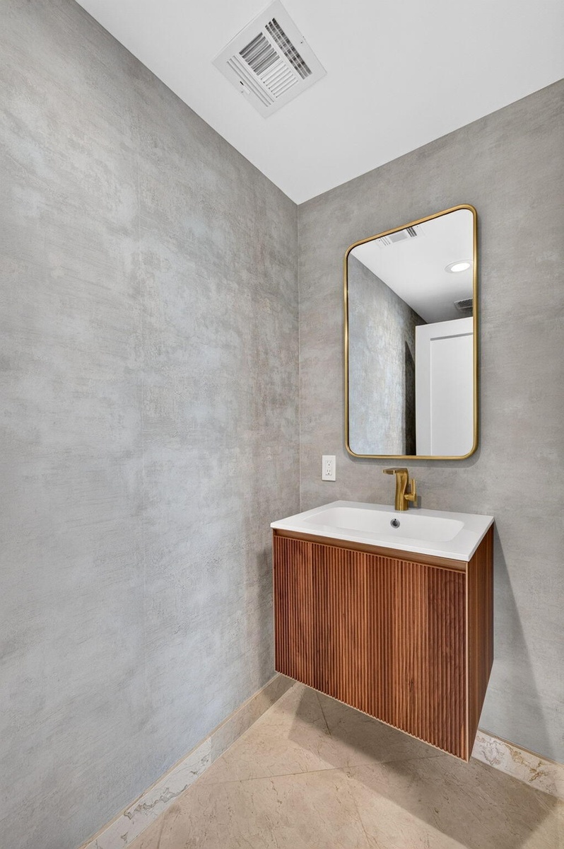 Floating wood-finish vanity with a fluted texture, white integrated sink, and gold-finish faucet