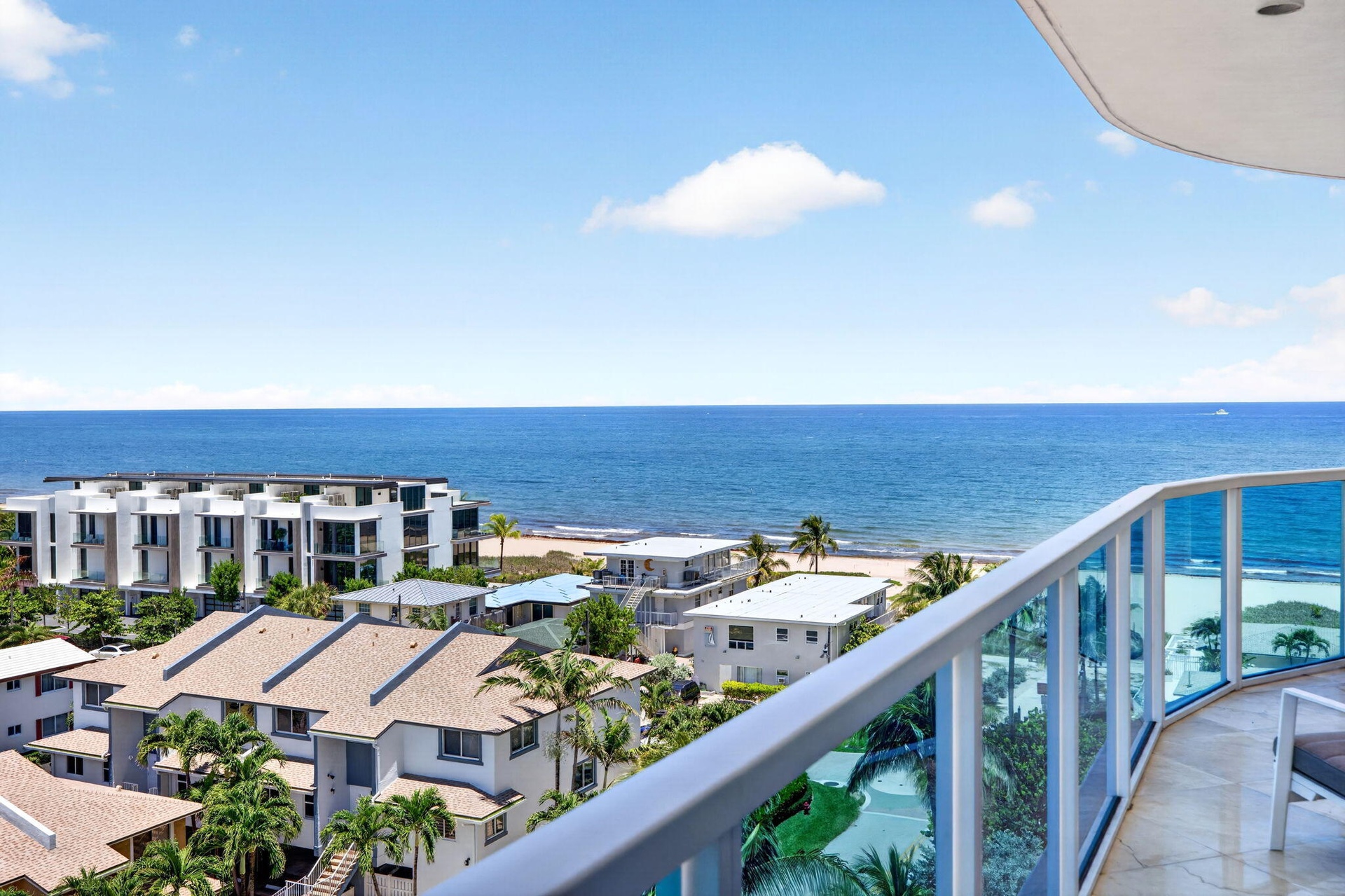 Expansive ocean scenery with a curved balcony featuring glass panel railings and marble flooring