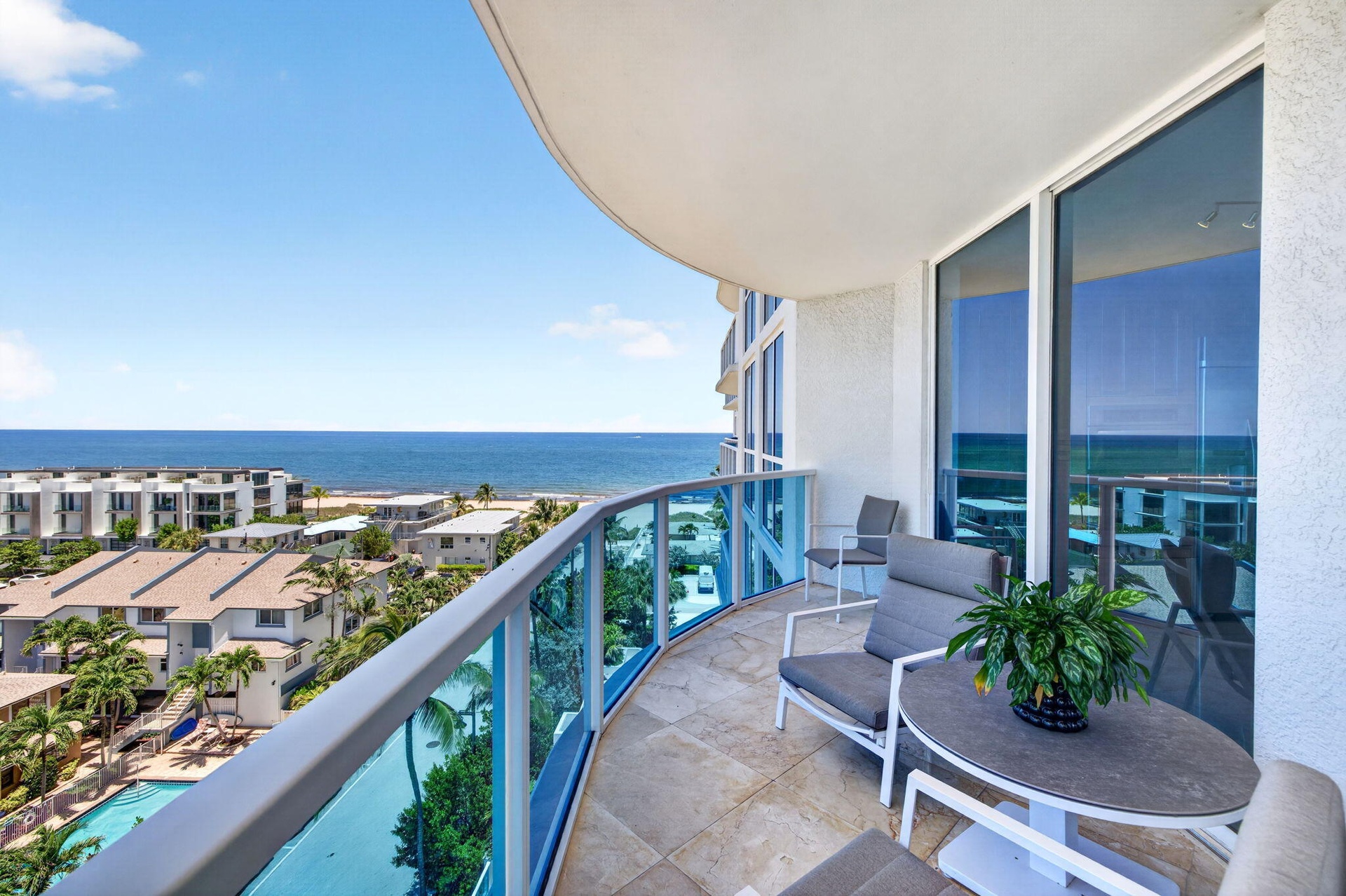 Curved balcony with glass railing, marble flooring, and sliding glass doors