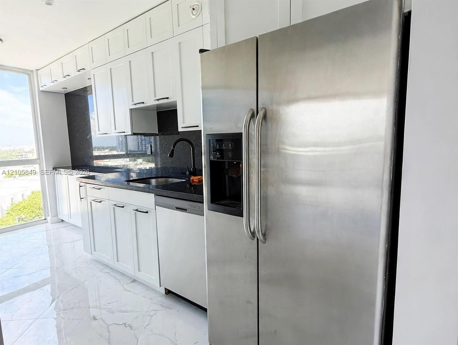 Kitchen featuring white shaker-style cabinetry, dark stone countertops, stainless steel side-by-side refrigerator, matte black gooseneck faucet, and l