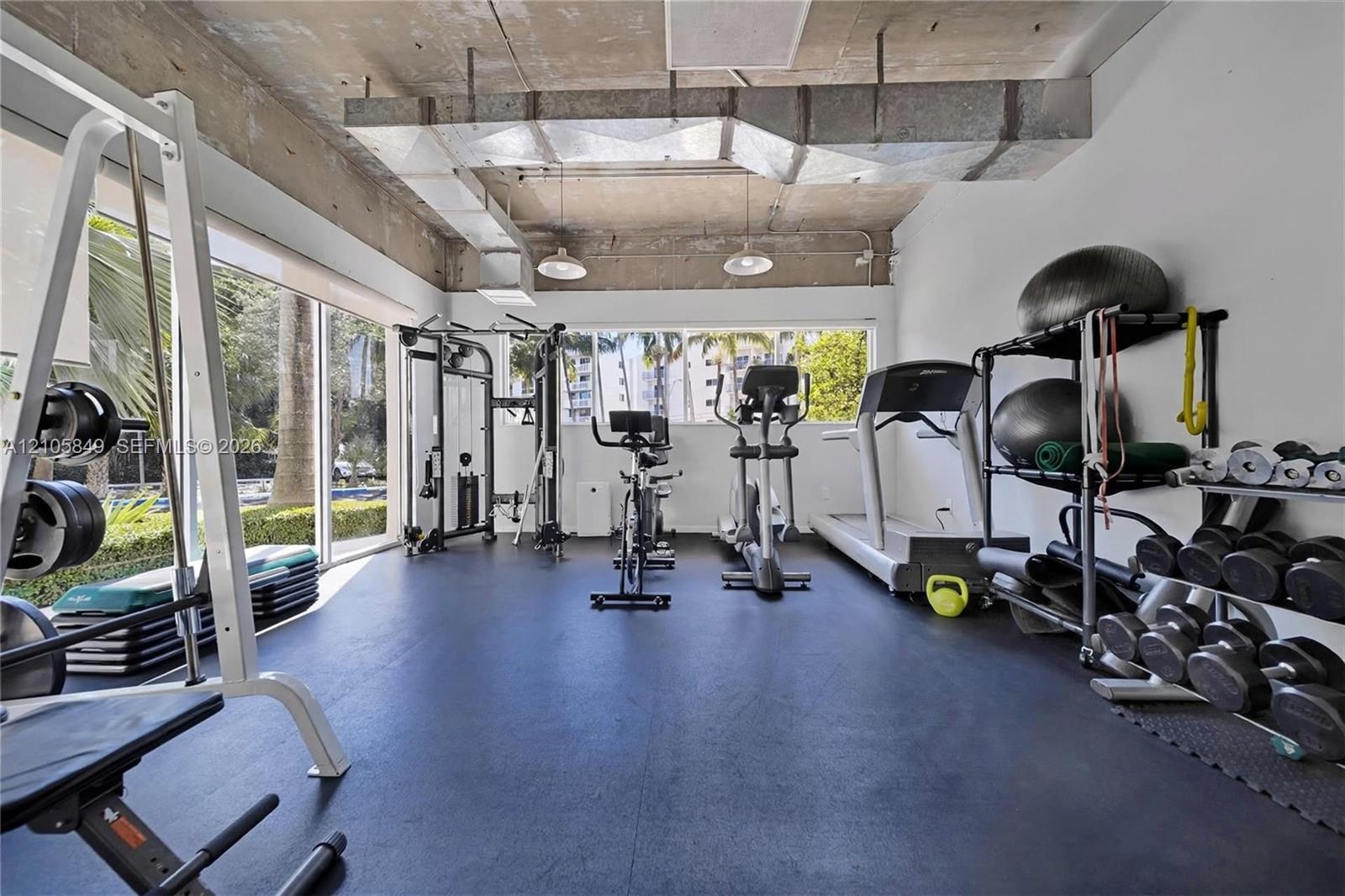 Industrial-style space featuring exposed concrete ceilings, floor-to-ceiling windows, and impact-resistant rubber flooring