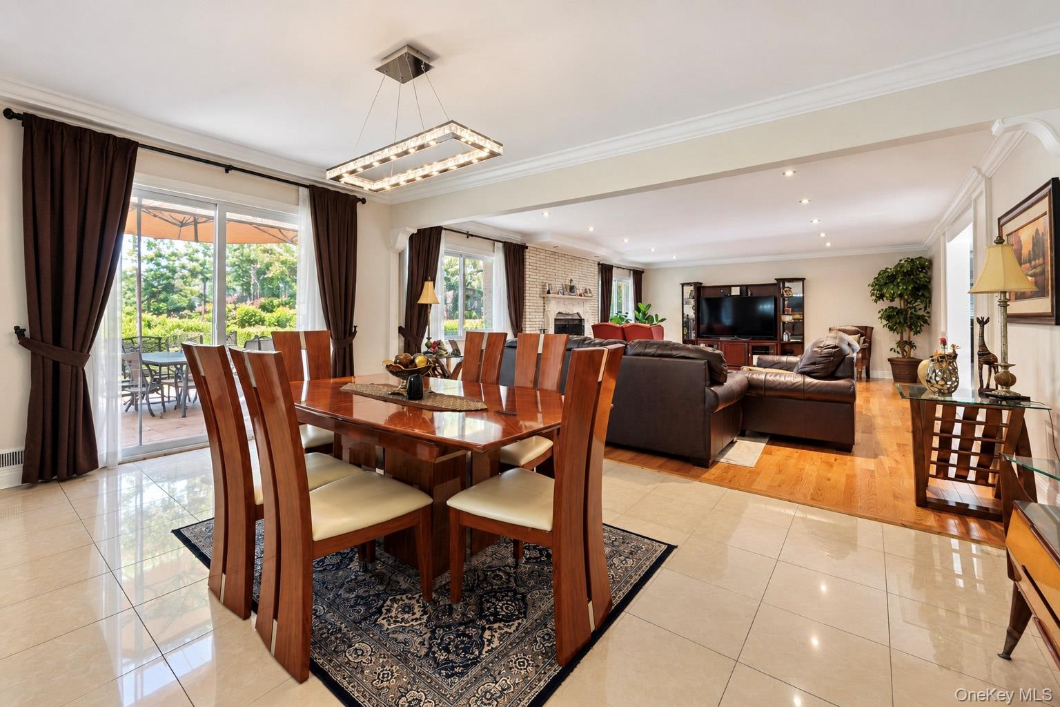 Ceramic tile flooring, crown molding, rectangular multi-light chandelier, and sliding glass doors