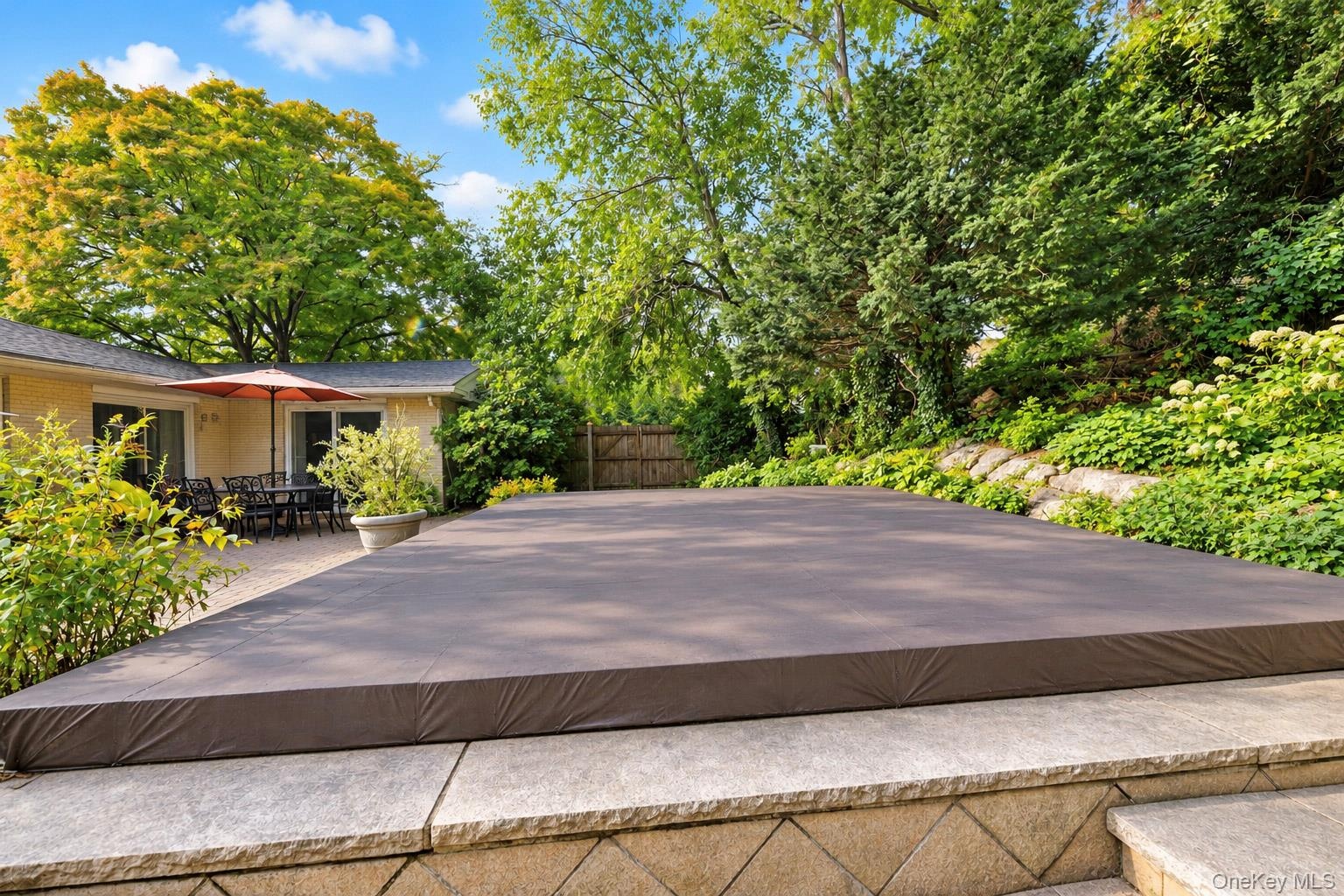 Stone-paved patio area with stone-retaining wall features and mature landscaping