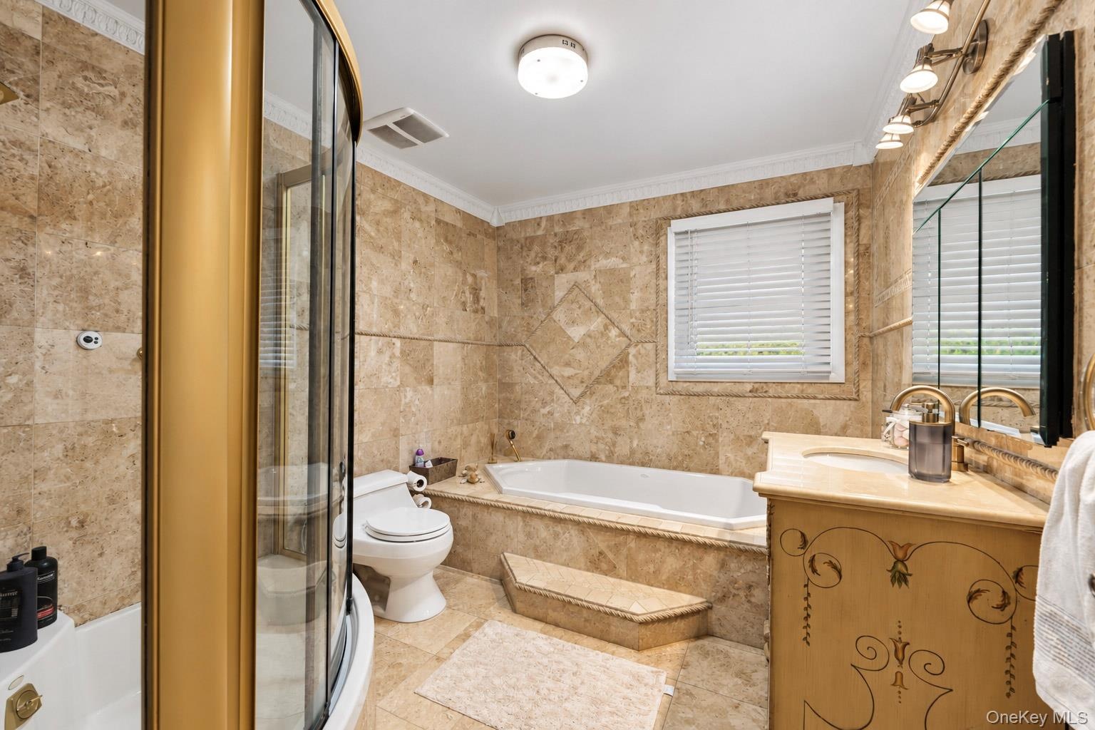 Bathroom featuring floor-to-ceiling stone tile, a glass-enclosed corner shower, a built-in soaking tub with a stone surround, and an integrated stone-