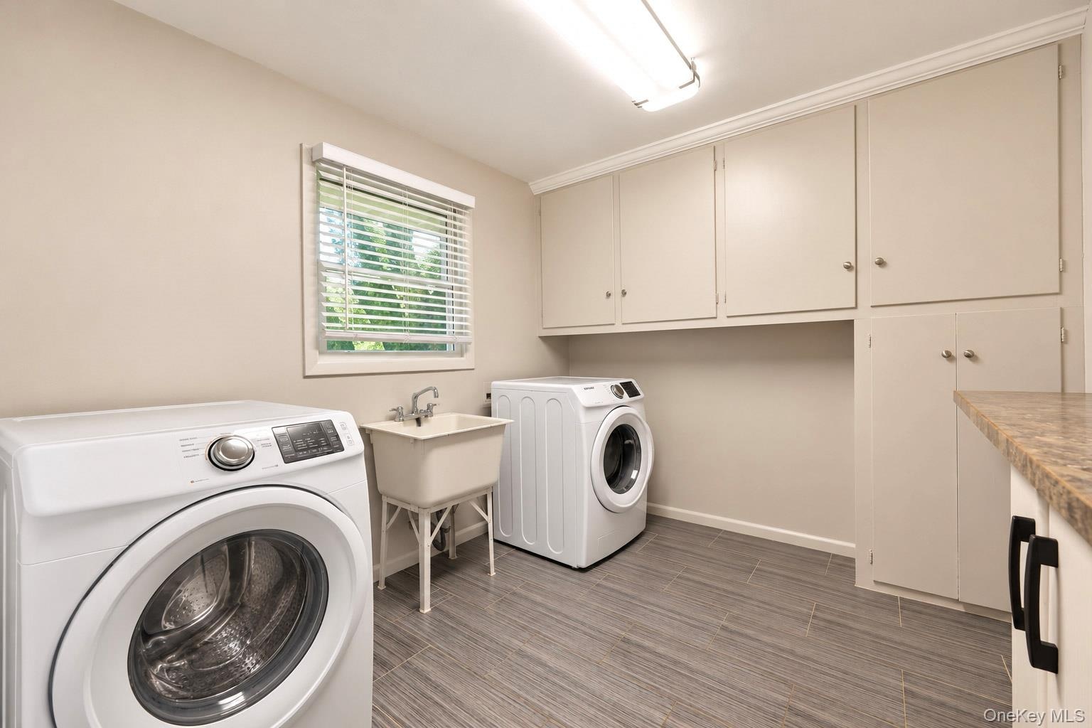Laundry area featuring wood-finish flooring, extensive built-in cabinetry, laminate countertops, a utility sink, and recessed lighting
