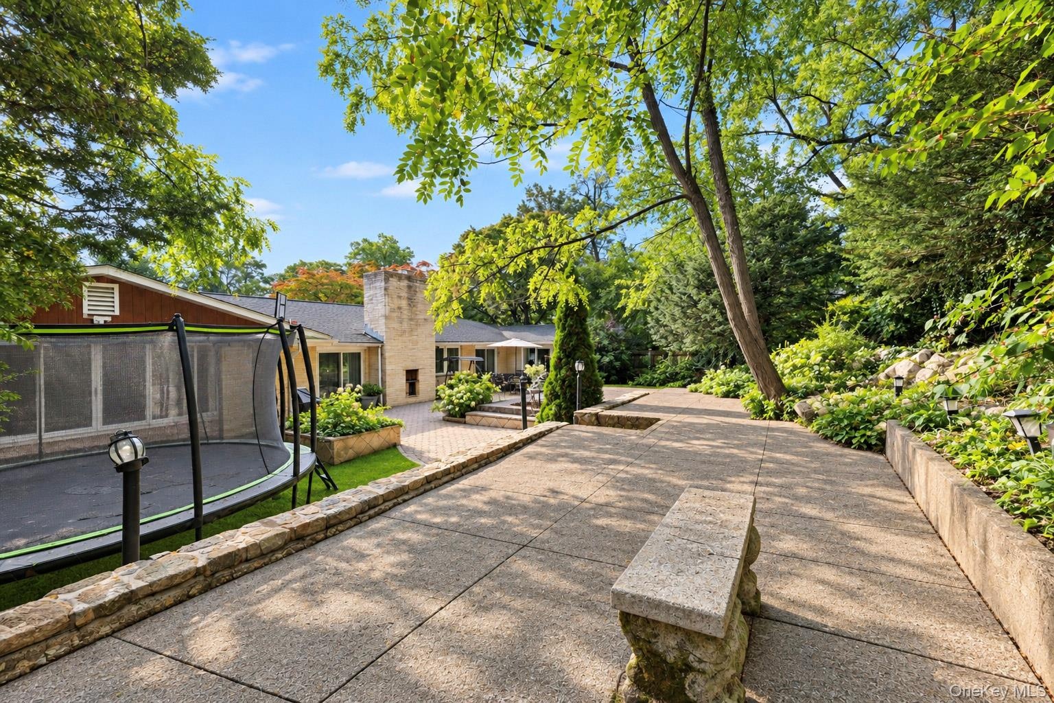 Spacious brick patio featuring a masonry chimney, sliding glass doors, and light-colored brick exterior siding