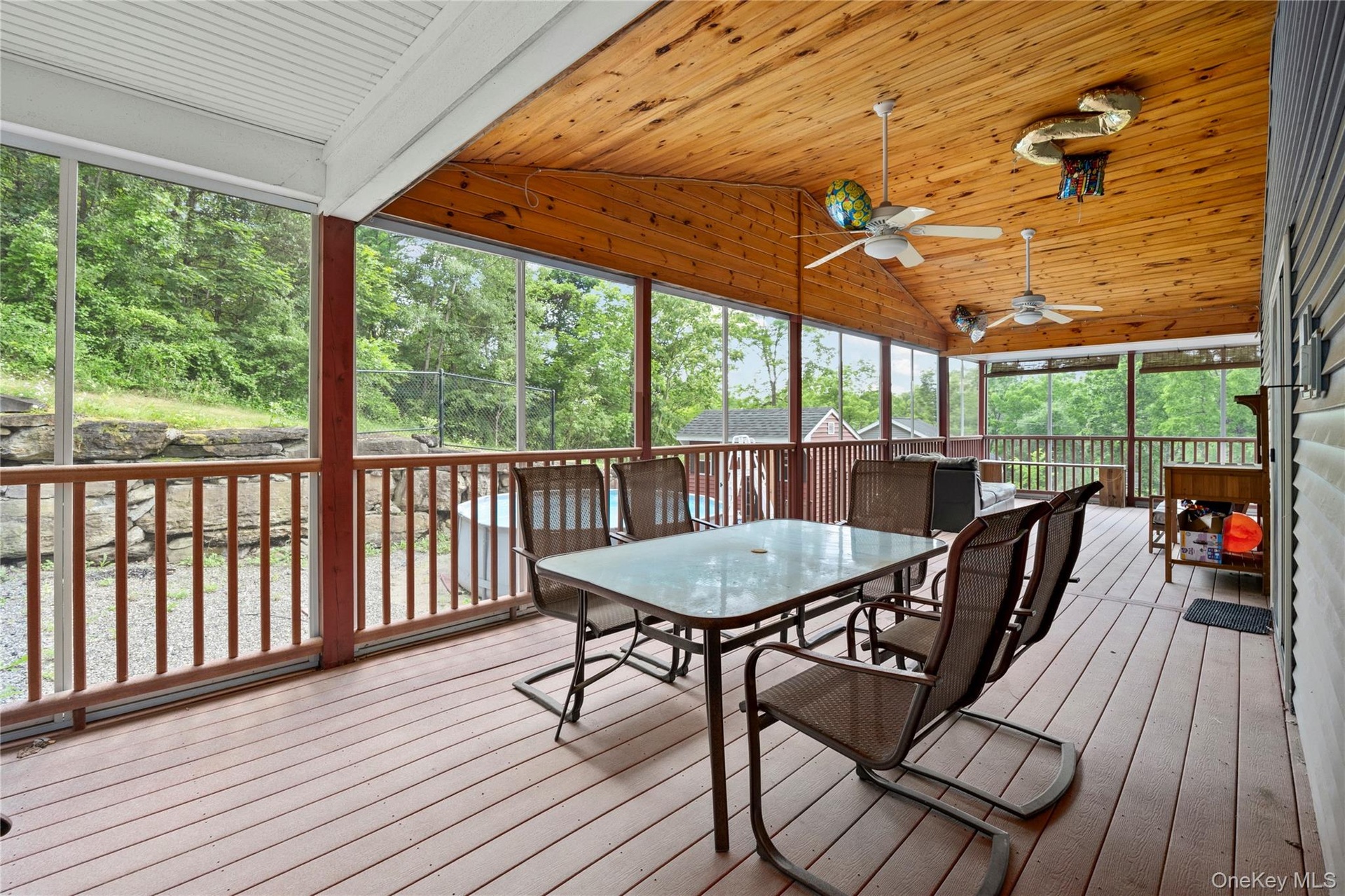 Screened in porch with vaulted ceiling, outdoor dining area, and ceiling fan